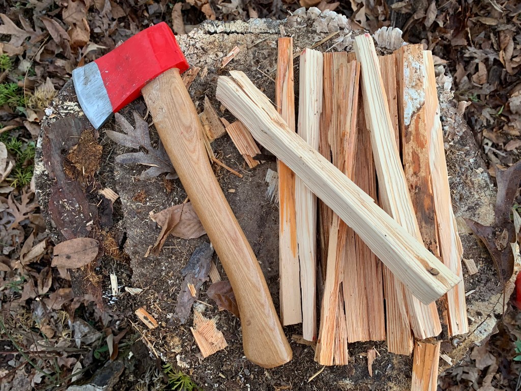 An axe resting on freshly split kindling on a tree stump
