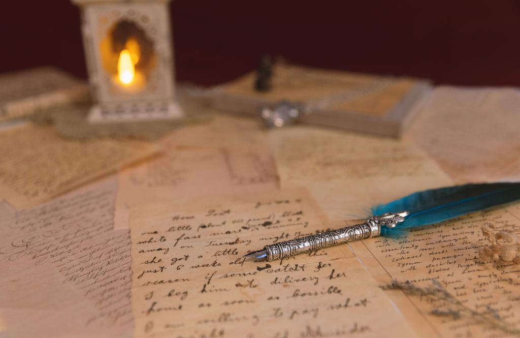 Handwritten letters and a quill pen on a table beside a glowing lantern