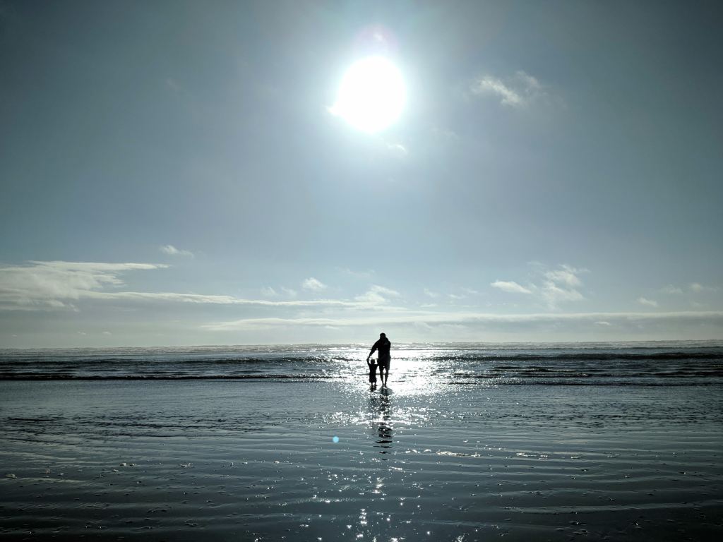 A lone figure walking on a shimmering beach under a bright sun