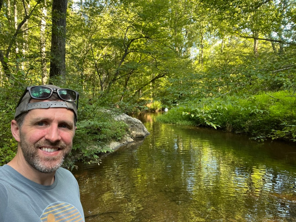 Mitch Yowell by a stream in the woods
